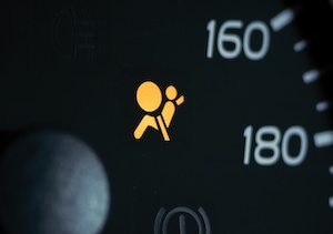 Dashboard with an illuminated airbag warning light, depicted as a seated figure with a circle in front.